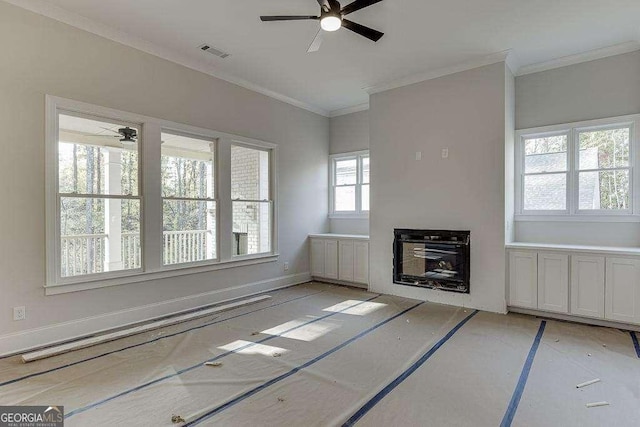 unfurnished living room featuring crown molding, a fireplace, visible vents, a ceiling fan, and baseboards