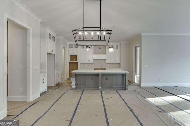 kitchen featuring a spacious island, glass insert cabinets, ornamental molding, light countertops, and white cabinetry