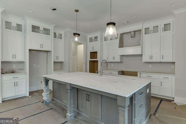 kitchen featuring white cabinets, a large island, glass insert cabinets, hanging light fixtures, and light stone countertops