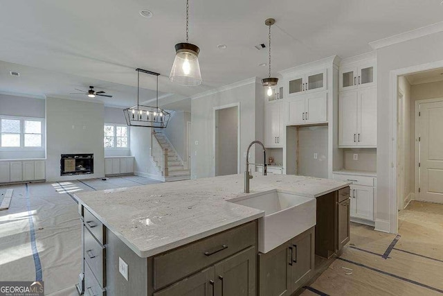 kitchen featuring glass insert cabinets, white cabinetry, a center island with sink, and a sink