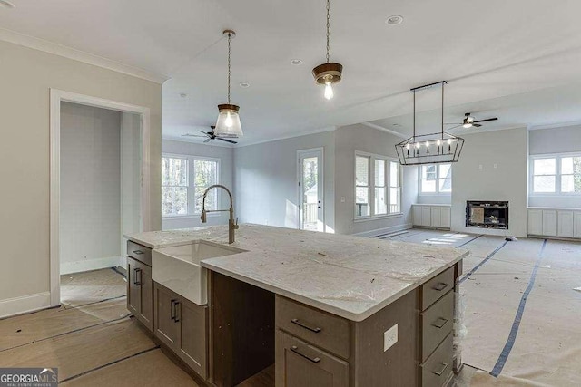 kitchen featuring a center island with sink, ornamental molding, open floor plan, and a sink