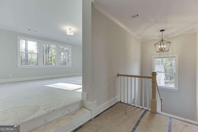 empty room featuring baseboards, visible vents, a chandelier, and crown molding