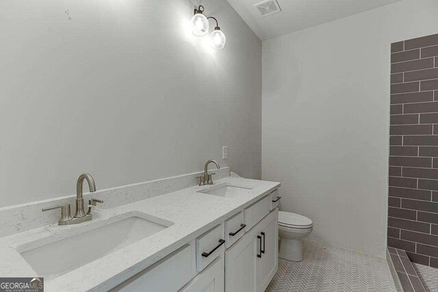 full bath with visible vents, a sink, toilet, and double vanity