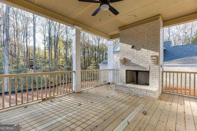 deck featuring an outdoor brick fireplace and ceiling fan