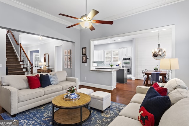 living area featuring baseboards, dark wood finished floors, stairs, crown molding, and ceiling fan with notable chandelier