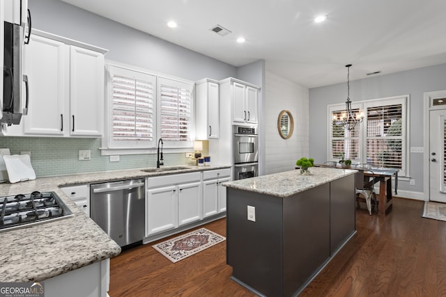 kitchen featuring dark wood-style floors, a center island, appliances with stainless steel finishes, white cabinetry, and a sink