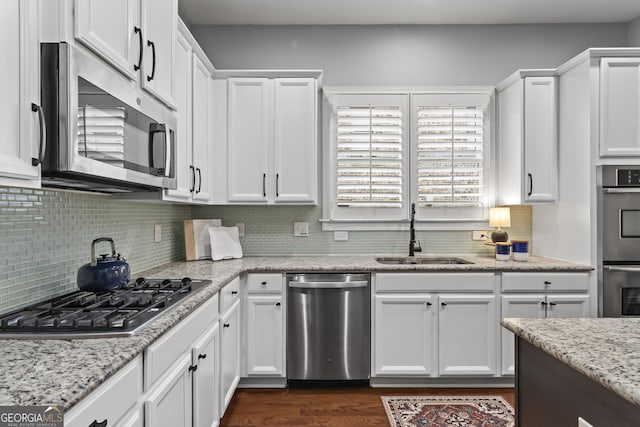 kitchen featuring stainless steel appliances, dark wood-type flooring, a sink, white cabinetry, and tasteful backsplash