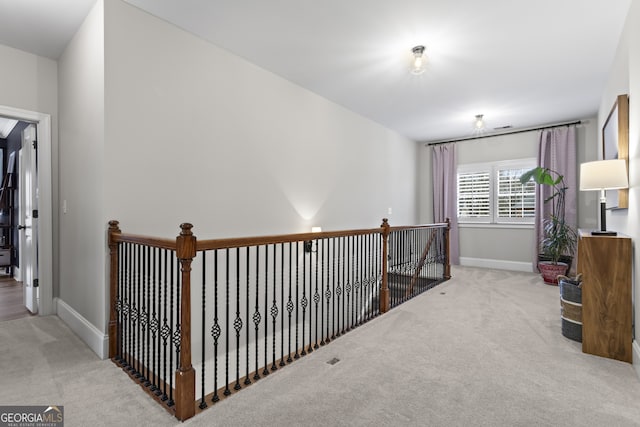 hallway featuring visible vents, baseboards, and carpet flooring