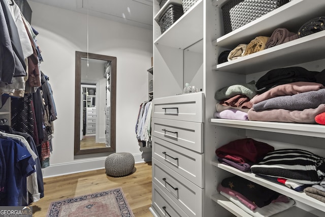 walk in closet featuring light wood finished floors and attic access