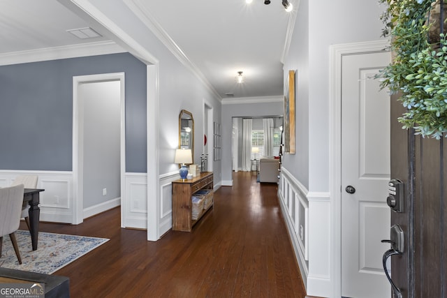 foyer entrance featuring crown molding, visible vents, dark wood-type flooring, and wainscoting