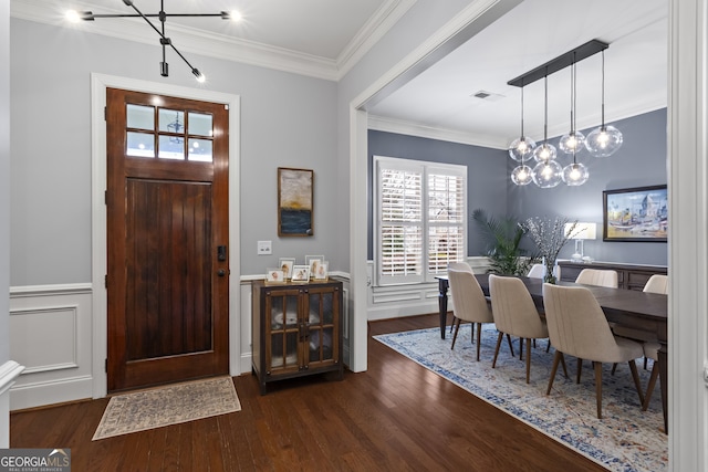 entryway with dark wood-type flooring, wainscoting, visible vents, and crown molding