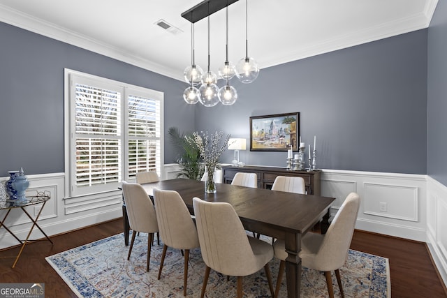 dining area featuring a chandelier, visible vents, crown molding, and wood finished floors