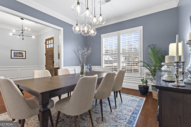 dining room featuring an inviting chandelier, crown molding, wood finished floors, and wainscoting