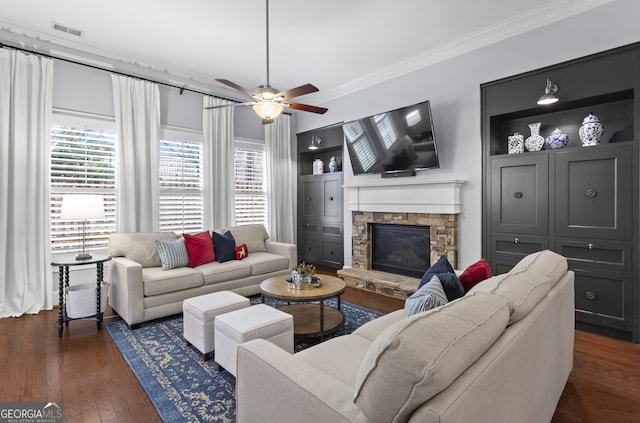 living area with plenty of natural light, dark wood finished floors, crown molding, and a stone fireplace