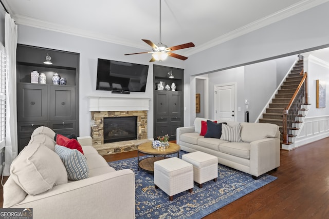 living area with a fireplace, wood finished floors, built in features, stairs, and ornamental molding