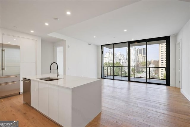 kitchen with light wood-type flooring, modern cabinets, a sink, expansive windows, and appliances with stainless steel finishes