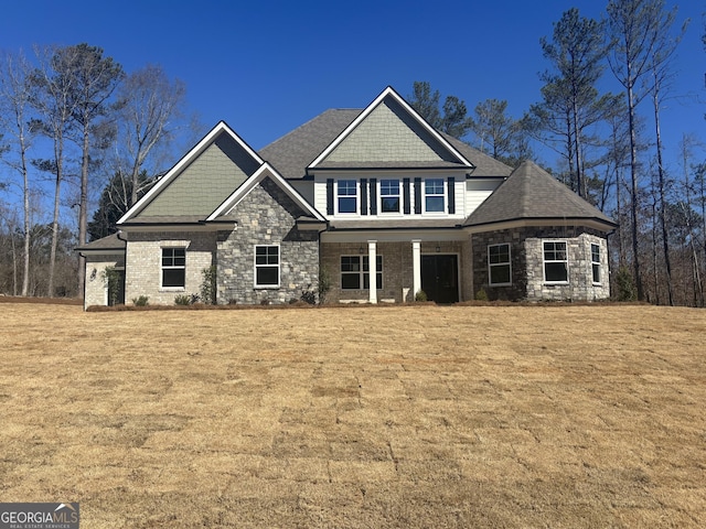 craftsman-style house featuring stone siding and a front lawn