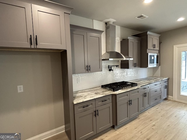 kitchen with stainless steel appliances, wall chimney range hood, gray cabinets, and visible vents