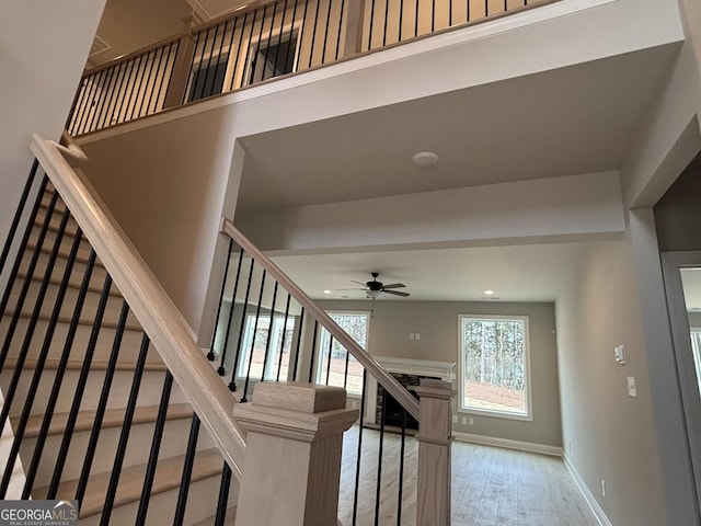 stairway with a fireplace, recessed lighting, a ceiling fan, wood finished floors, and baseboards