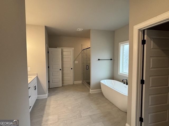 bathroom with a stall shower, a freestanding tub, vanity, and baseboards