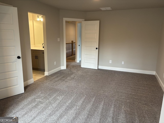 unfurnished bedroom with carpet floors, visible vents, a sink, and baseboards