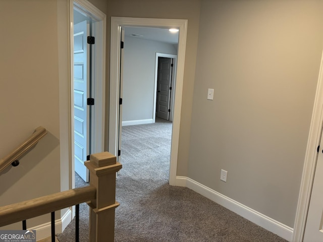 hall featuring an upstairs landing, carpet flooring, and baseboards