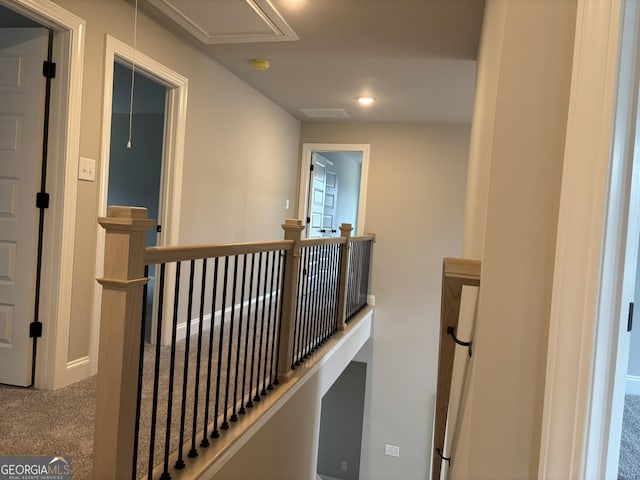 hall featuring attic access, carpet flooring, visible vents, and an upstairs landing