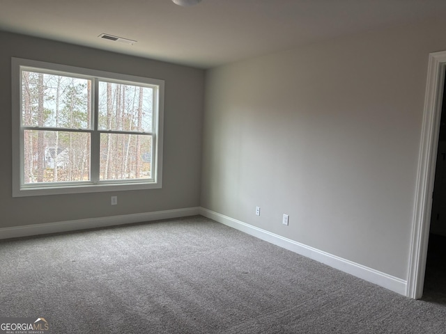 empty room featuring carpet flooring, visible vents, and baseboards