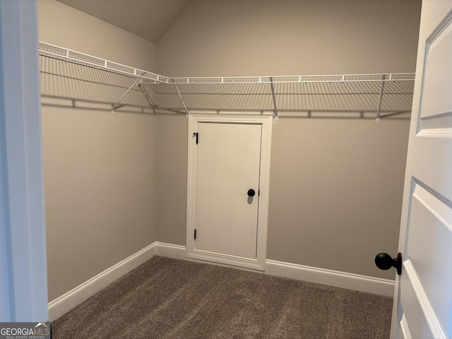 walk in closet with lofted ceiling and dark carpet