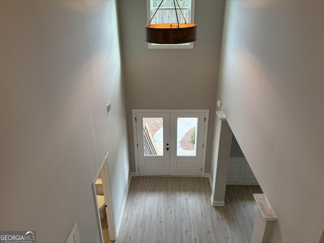 entryway with a wealth of natural light, a high ceiling, wood finished floors, and french doors