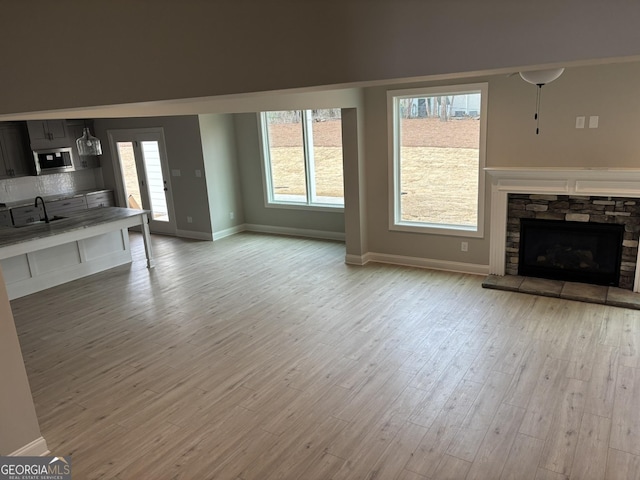 unfurnished living room with a sink, a fireplace, plenty of natural light, and wood finished floors