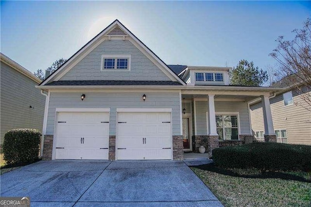 craftsman house with a garage, stone siding, and driveway