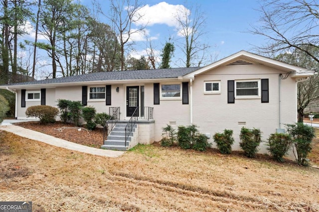 ranch-style home with a shingled roof, crawl space, brick siding, and a front lawn