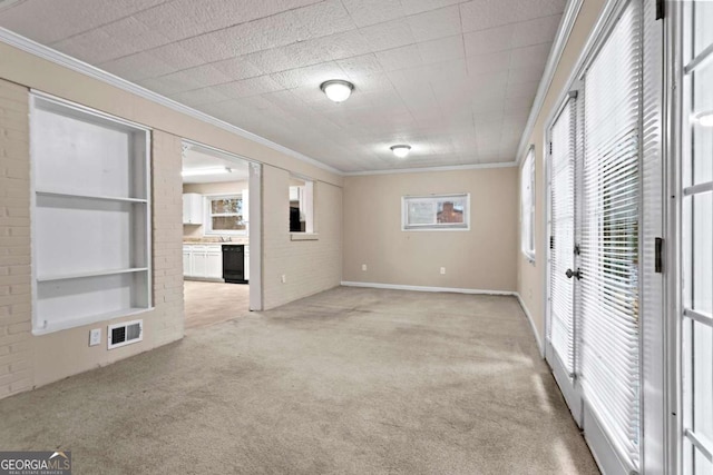 spare room with ornamental molding, light colored carpet, visible vents, and built in features