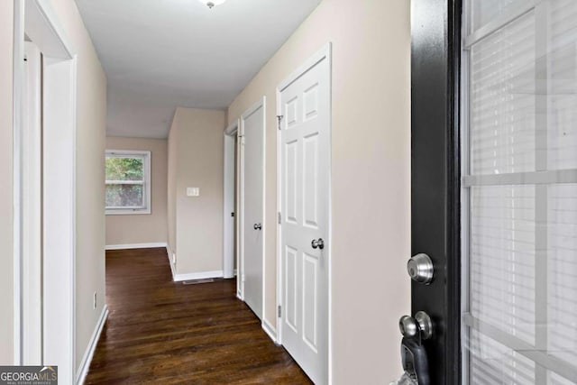 hall featuring baseboards and dark wood-type flooring