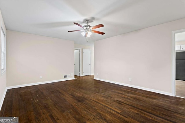 spare room featuring dark wood-style flooring, visible vents, and baseboards