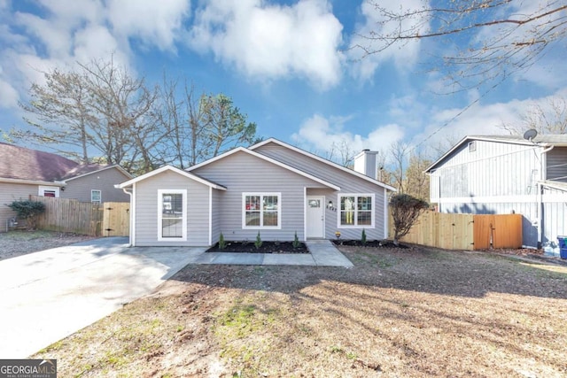 bungalow-style home featuring a chimney and fence