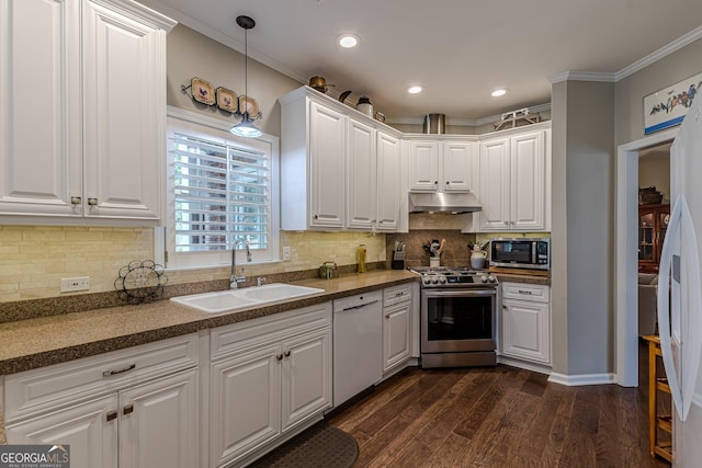 kitchen with white cabinets, dark countertops, appliances with stainless steel finishes, under cabinet range hood, and a sink