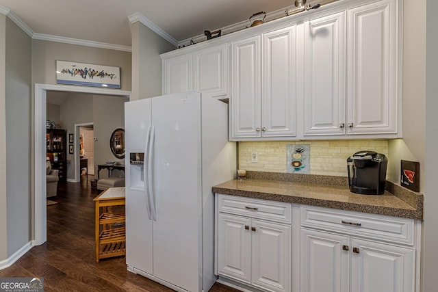 kitchen featuring dark countertops, white fridge with ice dispenser, and white cabinetry