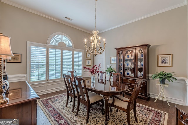 dining area featuring a wainscoted wall, crown molding, dark wood finished floors, visible vents, and an inviting chandelier