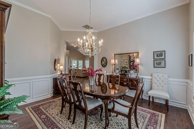 dining room with a chandelier, ornamental molding, dark wood-type flooring, and wainscoting