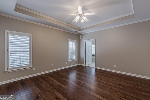 unfurnished room featuring ceiling fan, dark wood-style flooring, baseboards, a tray ceiling, and crown molding