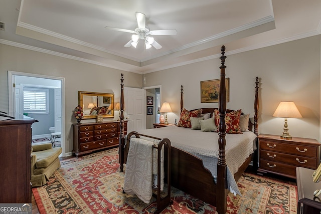 bedroom with a raised ceiling, visible vents, ensuite bathroom, ornamental molding, and a ceiling fan