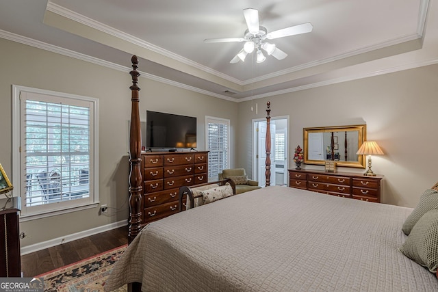 bedroom with baseboards, dark wood finished floors, a ceiling fan, a tray ceiling, and crown molding