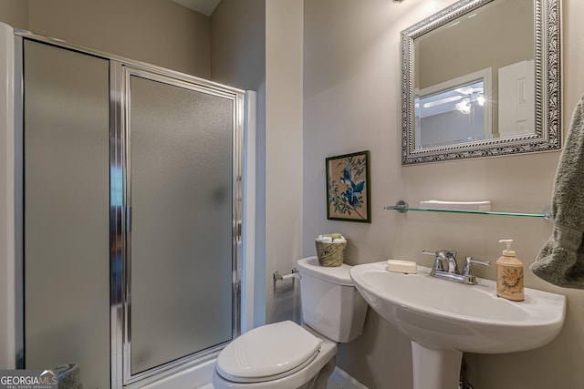 bathroom with a stall shower, a sink, and toilet