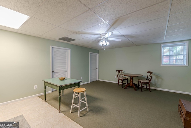 dining space featuring carpet floors, a drop ceiling, a ceiling fan, and baseboards