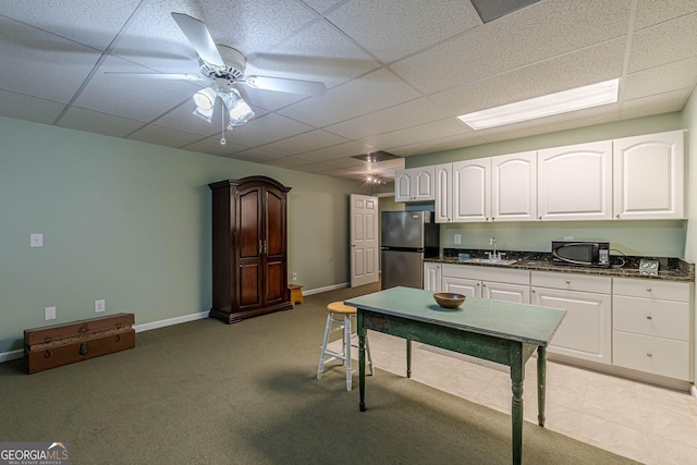 kitchen featuring white cabinets, ceiling fan, freestanding refrigerator, black microwave, and a sink