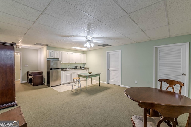 kitchen featuring light carpet, baseboards, freestanding refrigerator, and white cabinetry