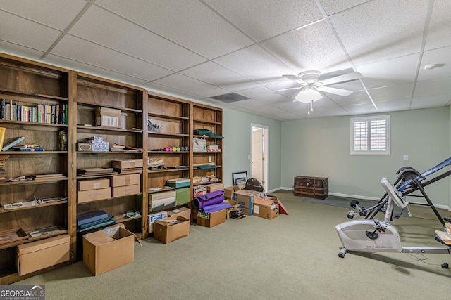 exercise room featuring a drop ceiling, carpet, a ceiling fan, and baseboards