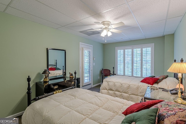 bedroom featuring a ceiling fan, baseboards, and a drop ceiling